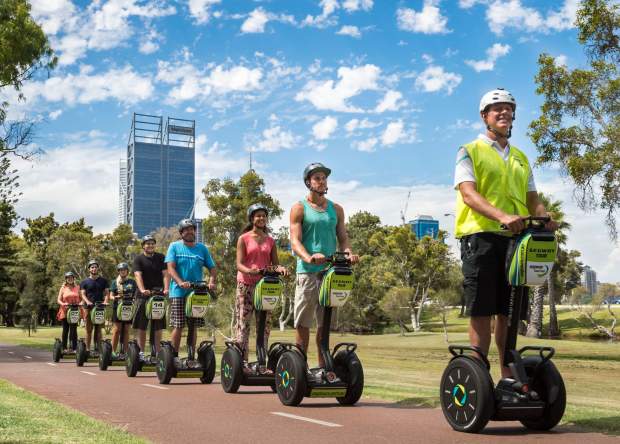 Group segway tour cruising along the path, with the city skyline in the background.