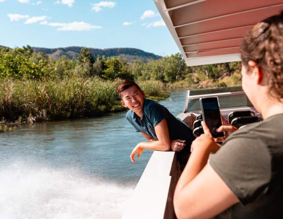 Passengers on a Triple J Ord River boat tour take a photo as the boat moves through the scenery