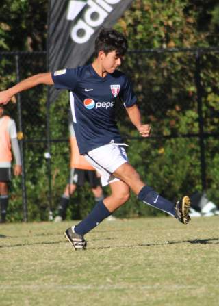 A soccer player kicks a soccer ball during a sports match.