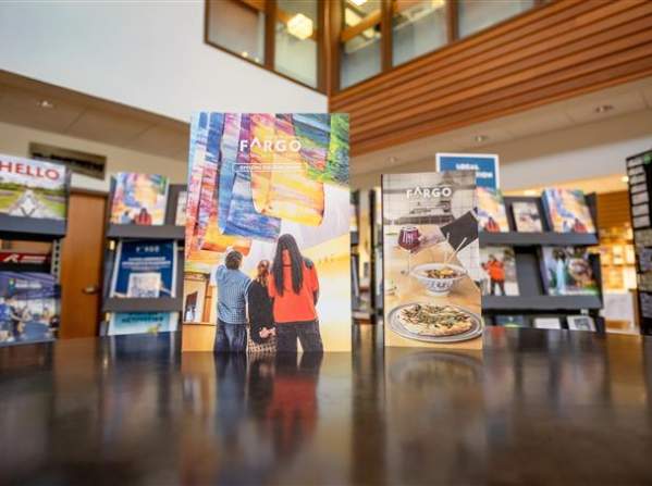The Visitor Guide and Dining Guide standing upright on a tabletop in teh FM Visitors Center.