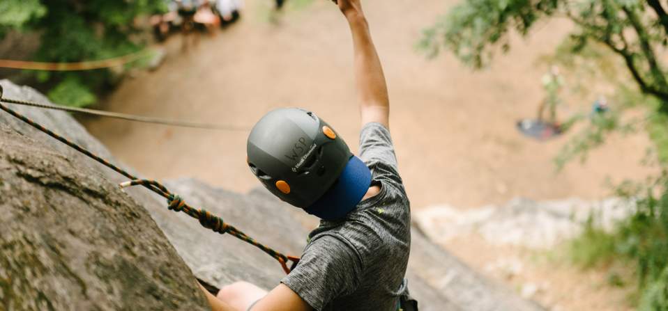 Man rock climbing on a cliff giving a thumbs up