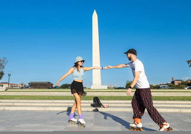 Couple roller skating in front of the Washington Monument