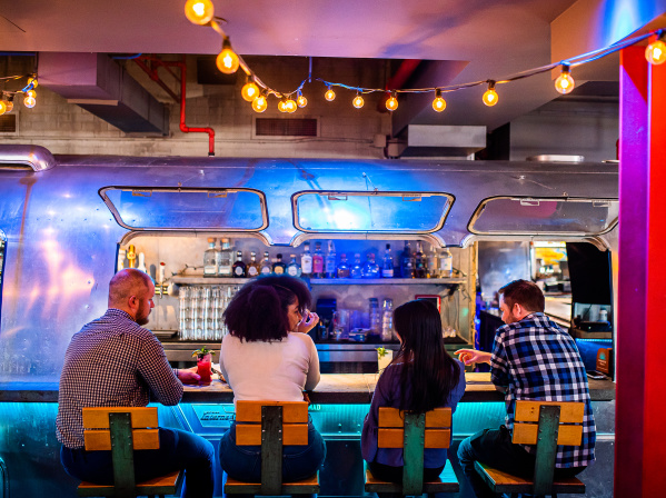 friends sitting at bar made from old silver RV