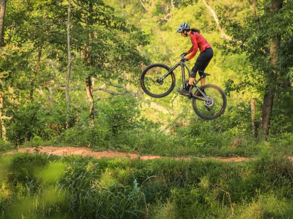 Anneke Beerten bikes through Bentonville, showcasing an outdoor art installation at The Momentary with vibrant sculptures against a scenic backdrop.