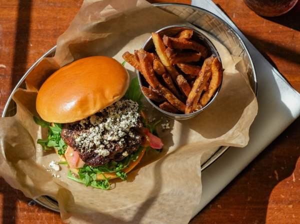 an open faced burger with blue cheese and a cup of french fries