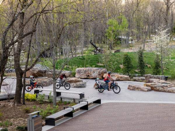 People riding various bicycles on scenic pathways within the Crystal Bridges grounds.