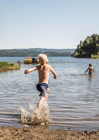 Ivrig gutt løper på sandstranden hos Sveastranda Camping