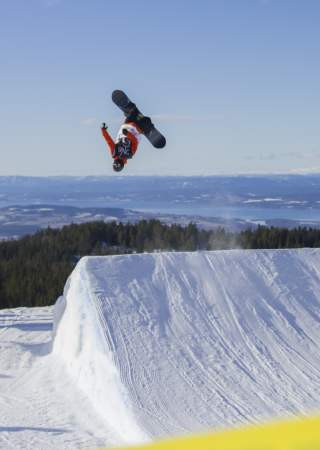 En snowboarder hopper høyt og tar en backflip i Ringkollen Alpintpark