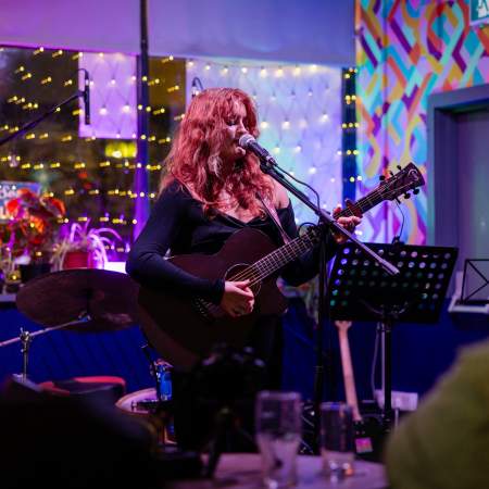 A woman playing an acoustic guitar on a small stage