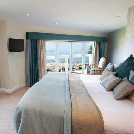 hotel bedroom with double bed and windows looking out over oxwich bay