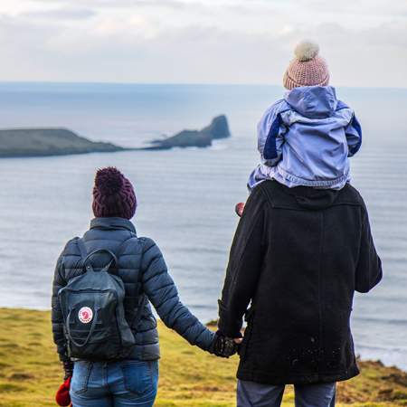 A man and a woman looking out at Worm's head. The man has a child on his shoulder.