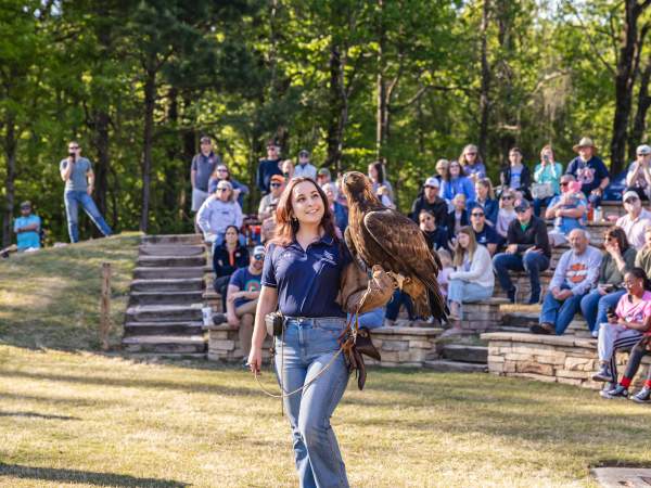 raptor center employeee standing in front of crowd with eagle