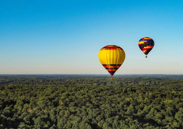 Two hot air balloons floating over Bloomington's rolling hills