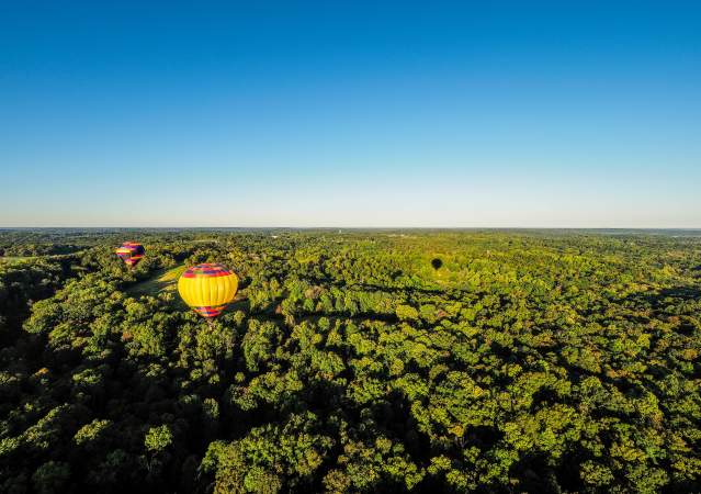 Two hot air balloons floating over the rolling hills of Monroe County