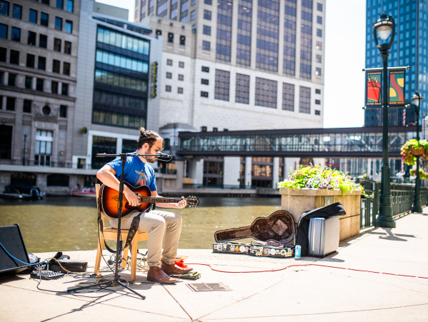 a male busker playing guitar on the Milwaukee RiverWalk