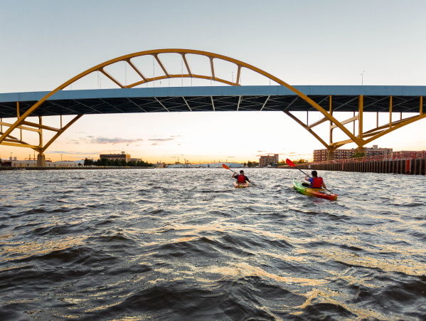 two kayakers kayaking under the Hoan Bridge