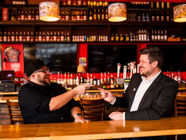 Two men pointing with the same name at each other and smiling