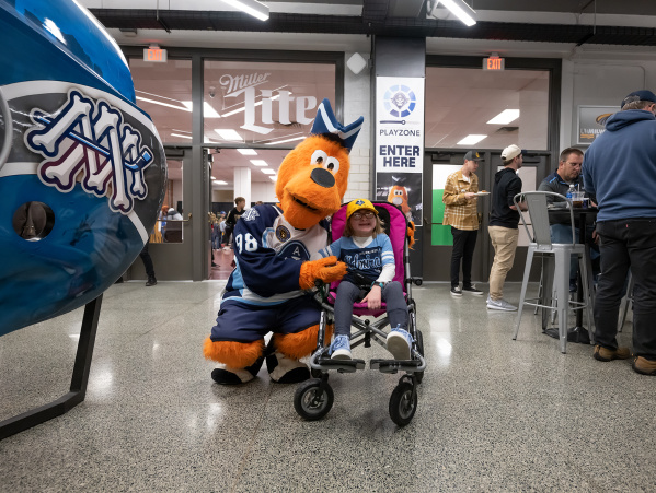 The Milwaukee Admirals mascot, Roscoe, with a young fan in a wheelchair.