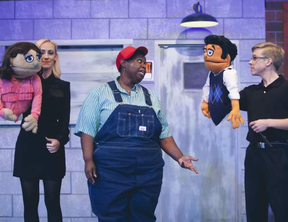ALT performance of Avenue Q. two people holding puppets talking to main character in the middle of them