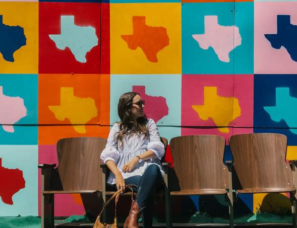 girl sitting in front of Texas mural on route 66 in amarillo