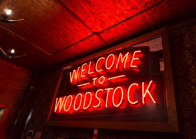 Neon Orange sign that says Welcome to Woodstock