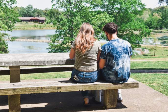 a young couple at a picnic table near a lake