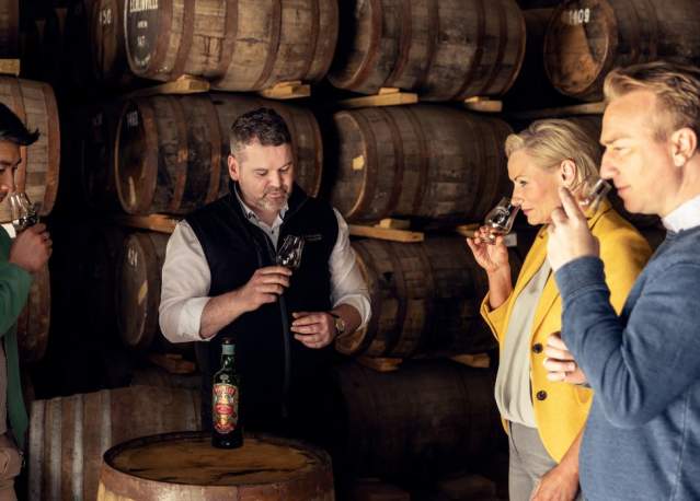 Group smelling whiskey with guide at distillery