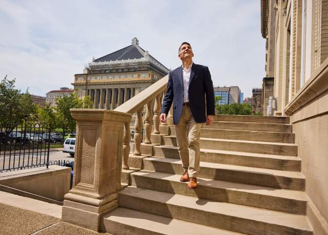 A man walks down the steps outside of a historic building in Pittsburgh.