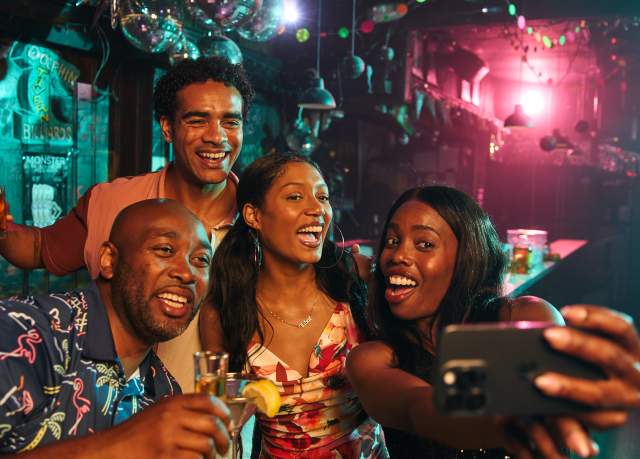 A group of African-American adults pose for a selfie in a nightclub.