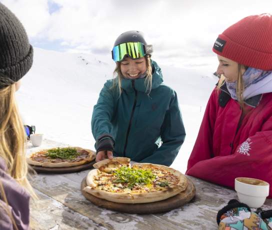 Friends eating pizza on the slopes at Cardrona Alpine Resort