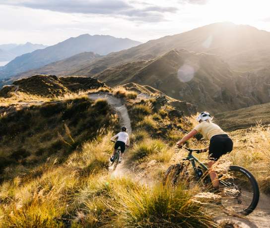Two people riding mountain bikes through the mountains