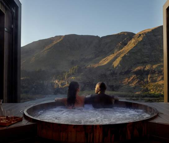 Two people in a hot tub with a beautiful mountain view