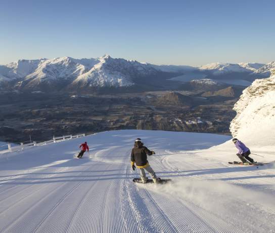 Snowboarders and skiers riding down snowy mountain
