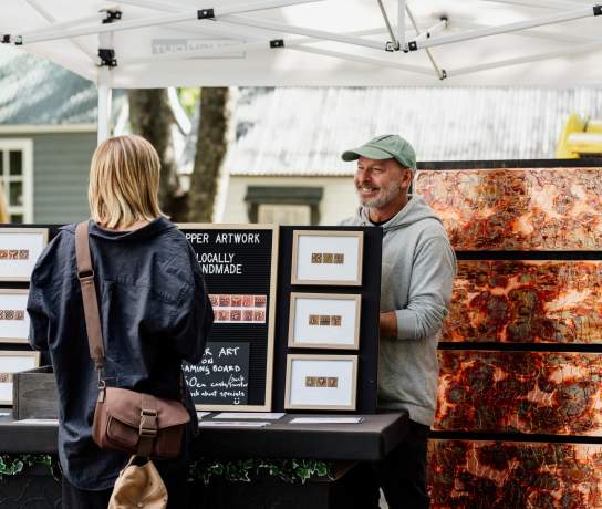 Women purchasing local artwork at the Arrowtown Farmers Market