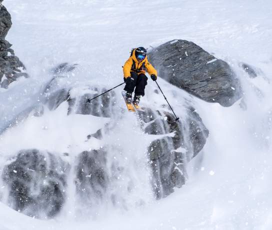 Freeskier Pete Oswald skiing down a rocky mountain face