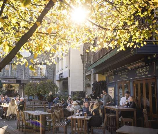 Groups of people dining alfresco at a pub on the waterfront in Queenstown