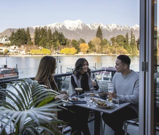 Three people Dining at Boardwalk with snowy mountains in the background