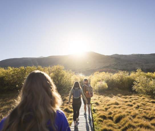 Photo from the point of view walking along the Glenorchy walkway with mountains and the rising sun ahead