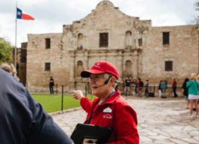 Tour guide with headpiece mircophone in front of the Alamo