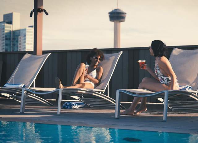 Two girls talking poolside on lounge chairs