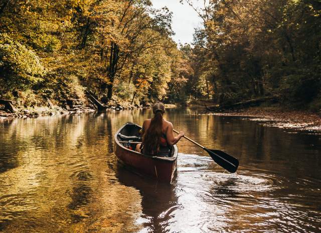 lady in a kayak on a creek in the fall