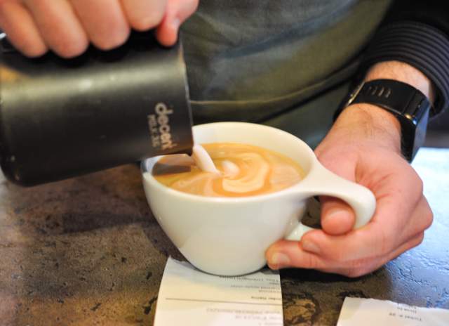 pouring milk into a coffee cup