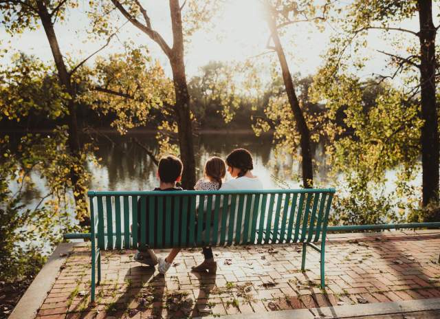 family on a bench by a river in the fall