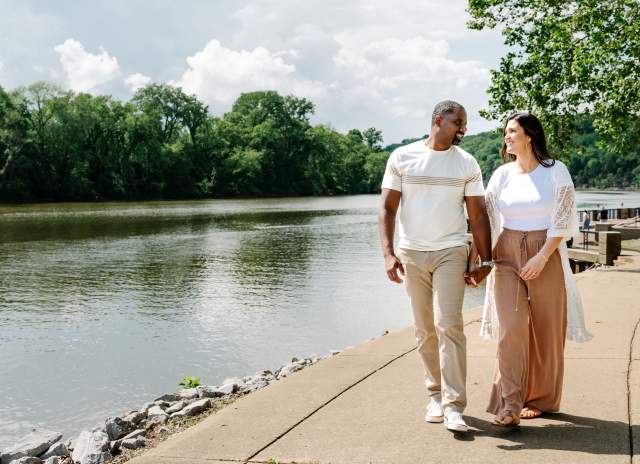 a man and woman walk along a riverside path