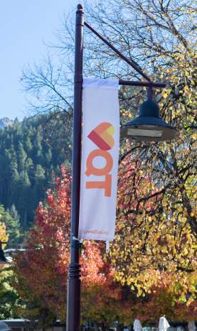 Love Queenstown flags displayed in the street with autumn trees and mountain in the background