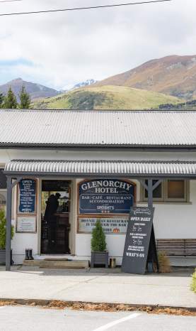 Exterior shot of Glenorchy hotel and pub which old school signage and mountains in the background