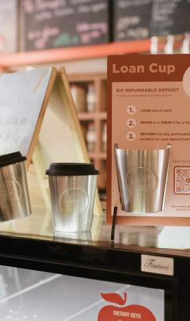Reusable loan coffee cups displayed on a cafe cabinet