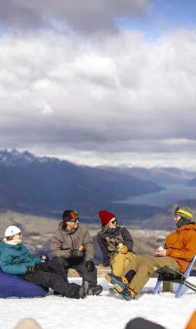 Group of skiers and snowboarders having a drink at the top of a mountain