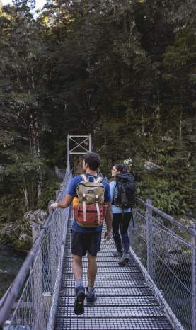 People crossing bridge into native bush at the start of the Routeburn Track
