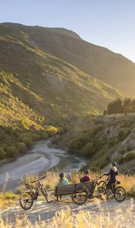 A group of cyclists taking a break next to Gibbston River